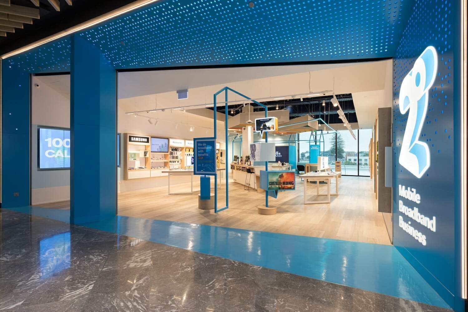 Modern retail store with bright blue exterior walls and glass storefront entrance, displaying interior merchandise and signage