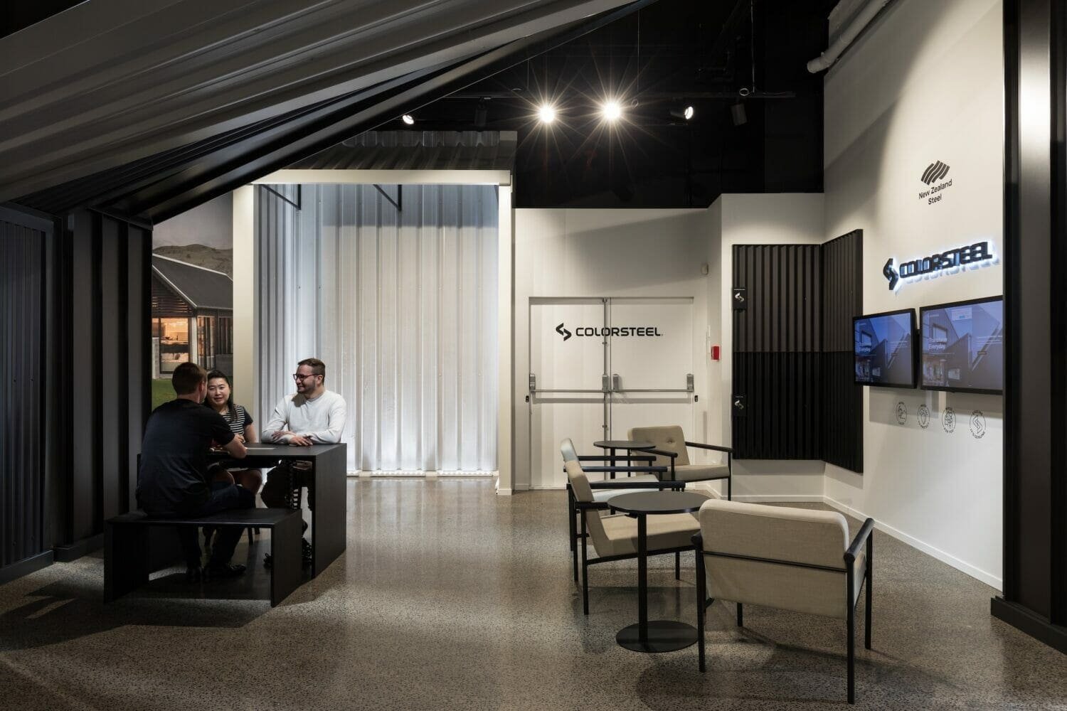 Modern showroom interior with display seating areas, product displays, and two people conversing near a white doorway