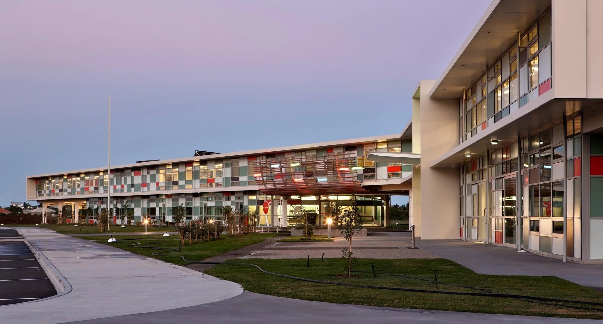 Modern commercial building complex at twilight with illuminated storefronts and contemporary architecture